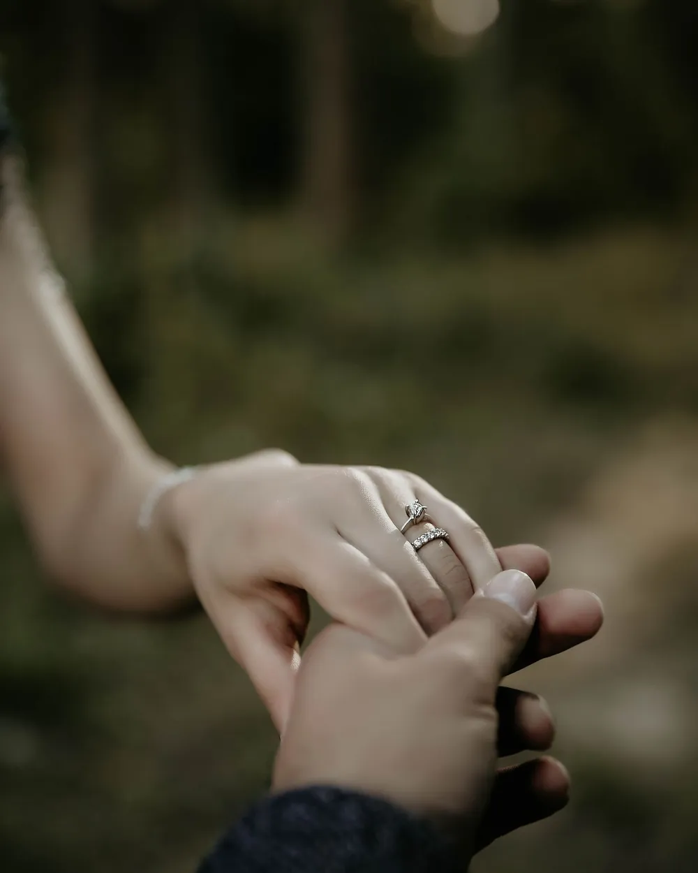 Pareja tomada de la mano con anillo de compromiso